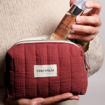 Pessoa a segurar a bolsa vermelha do coffret Éclat de Rose da Centifolia e um frasco de Sérum Intensificador de Hidratação (30ml), destacando os cuidados de rosto com ingredientes naturais.